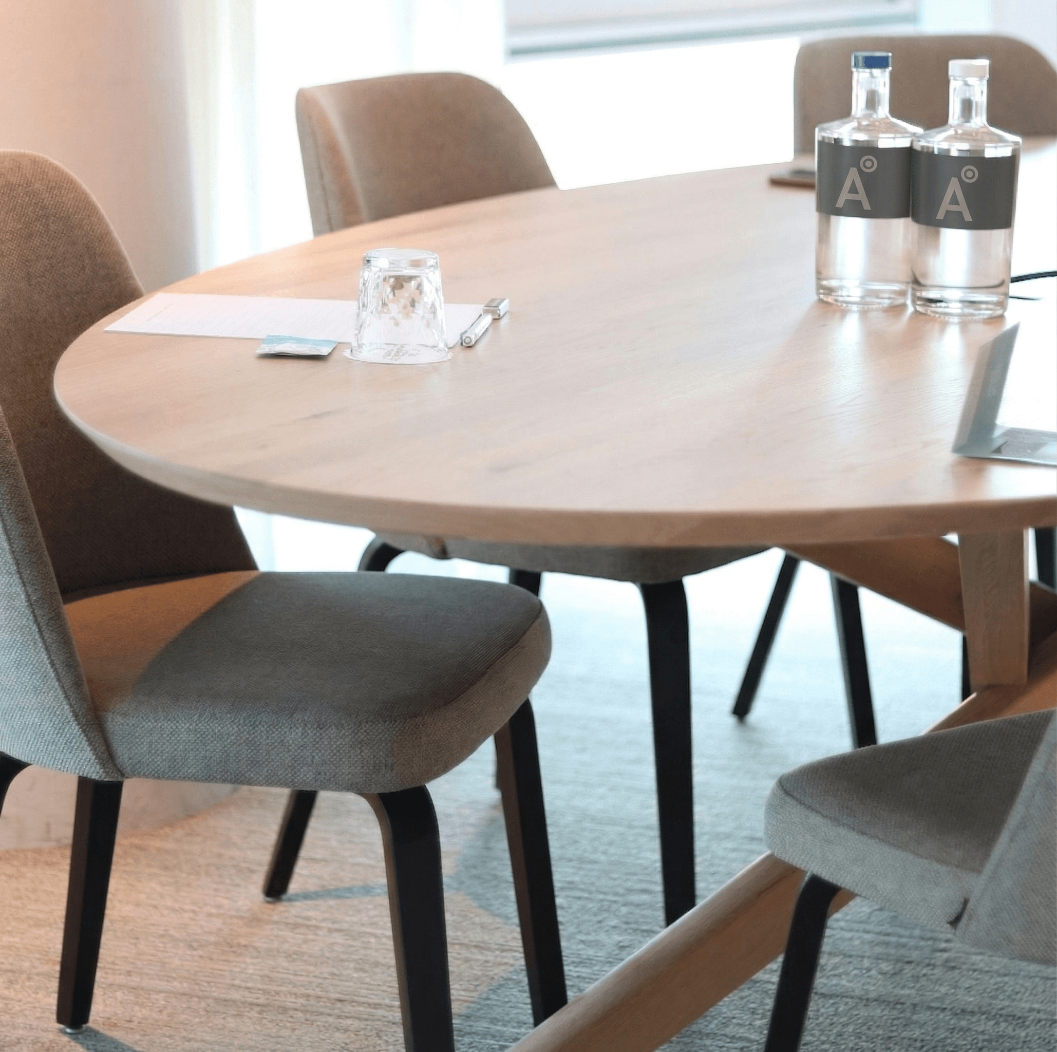 Sala de reuniones de ADUNAS con botellas de agua de marca — espacio de trabajo cercano y profesional.